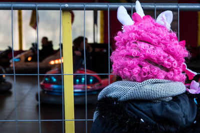 Rear view of person wearing pink wig while standing by gate