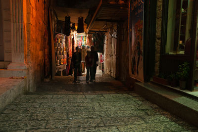 Rear view of people walking on street amidst buildings