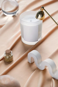 Creative still life composition with soya candle on creamy pastel background, extinguisher and