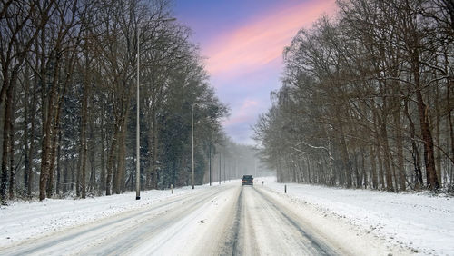 Driving in a snowstorm on a country road in the netherlands at sunset