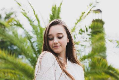 Close-up of smiling young woman against plants