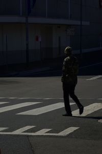 Rear view of man crossing road