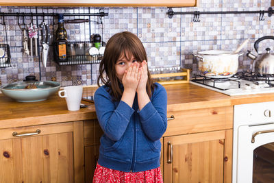 Girl looking away while standing in kitchen