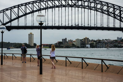 People on bridge with city in background