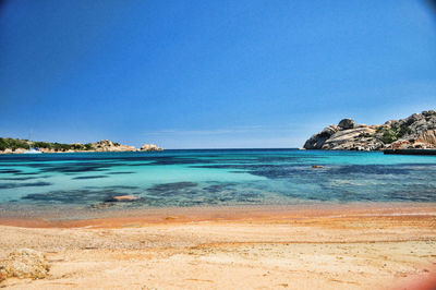 Scenic view of beach against clear blue sky