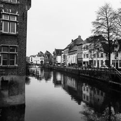 Buildings reflection in river against sky