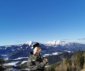 Full length of person on snowcapped mountain against clear blue sky