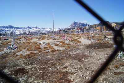 Cemetery against mountains seen through fence during winter
