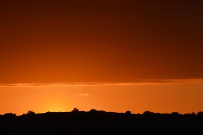 Silhouette landscape against dramatic sky during sunset