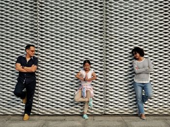 Full length portrait of girl standing with parents against wall