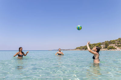 Happy teenagers playing volleyball in water at the vacation and fun