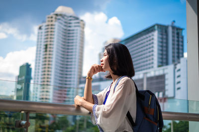 Woman standing by modern buildings in city