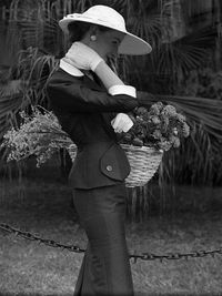 Midsection of woman holding umbrella while standing by plants