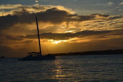 Silhouette ship sailing on sea against sky during sunset