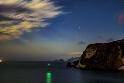 Boats moored on sea against sky at night