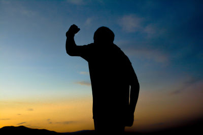 Silhouette man photographing against sky during sunset