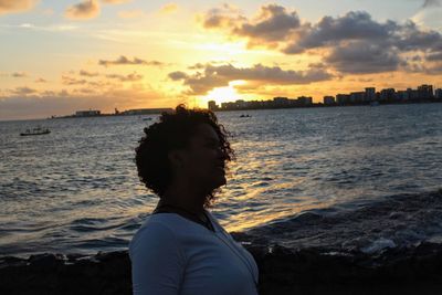 Man standing on beach against sky during sunset