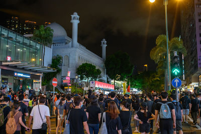 People on street amidst buildings in city at night