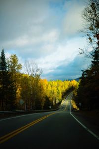 Country road against cloudy sky