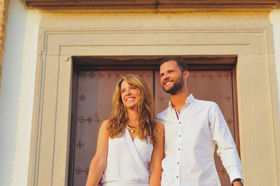 Low angle view of happy young couple looking away while standing in balcony