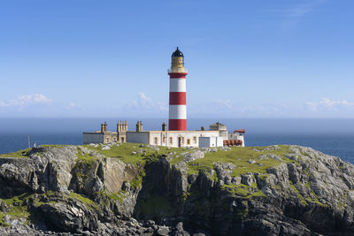 Lighthouse by sea against sky