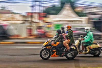 Rear view of man riding motor scooter on road