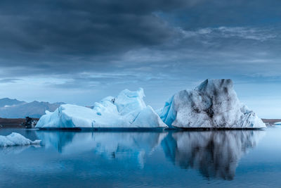 Iceberg floating in sea against sky at dusk