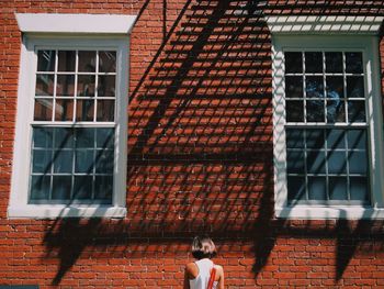 Rear view of woman standing against house