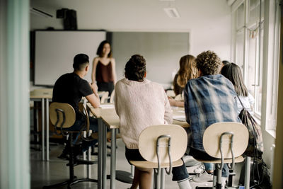 Junior high students studying while female teacher standing in classroom