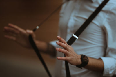 Close-up of hands holding trousers straps