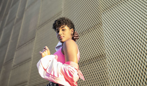 Young woman near wall during sunny day