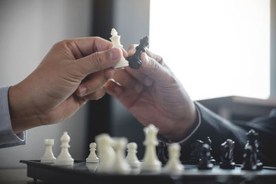 Cropped hands of friends holding king chess pieces by chess board