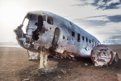 Damaged airplane on beach against sky