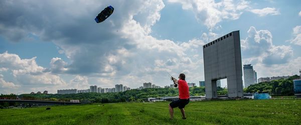 Man flying kite against cloudy sky