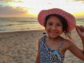 Close-up portrait of girl smiling while wearing hat at beach