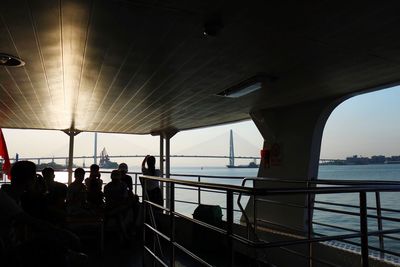 People on bridge over sea against sky