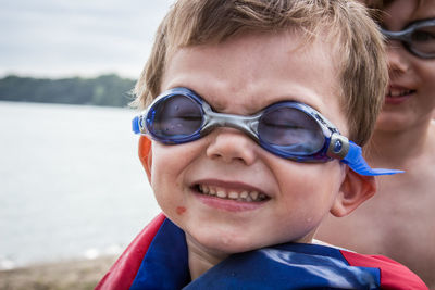 Close-up of boy with brother in swimming goggles at beach