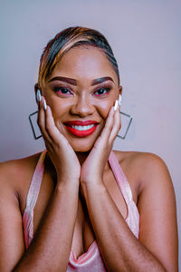 Portrait of smiling young woman against wall