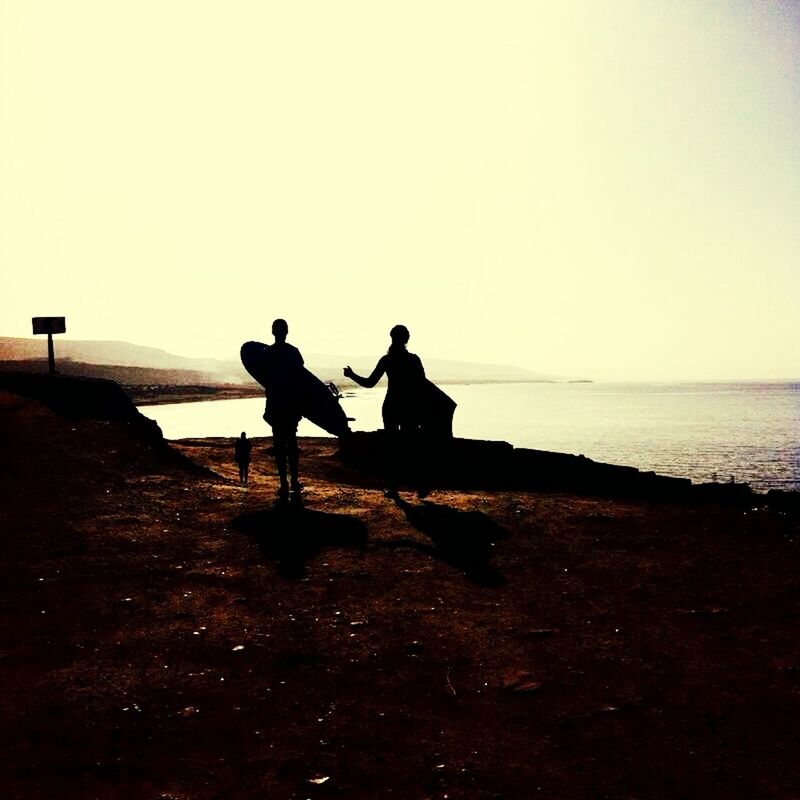 clear sky, copy space, men, silhouette, togetherness, sea, lifestyles, horizon over water, leisure activity, water, beach, full length, bonding, person, tranquility, tranquil scene, friendship