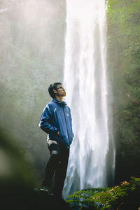 Man standing by waterfall