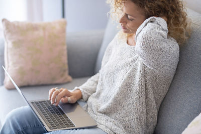 Midsection of woman using mobile phone while sitting on sofa