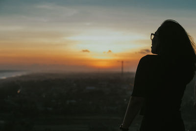 Silhouette woman standing against sky during sunset