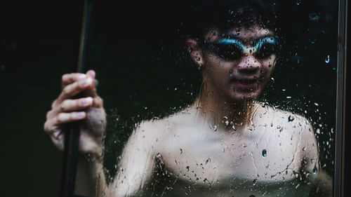 Shirtless young man holding frame while swimming in lake