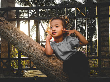 Portrait of young woman sitting on railing