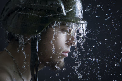 Close-up of wet young man over black background