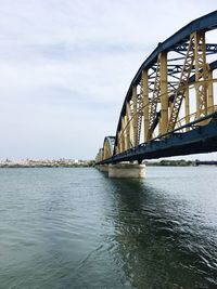 Bridge over river in city against sky