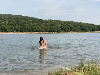 Rear view of woman in lake against sky