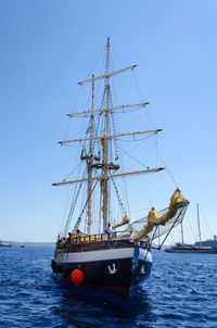 Sailboat sailing on sea against clear blue sky