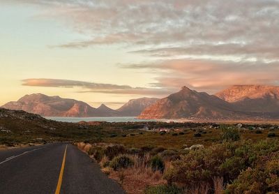 Road by mountains against sky during sunset