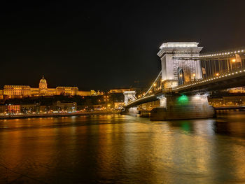 Illuminated bridge over river at night